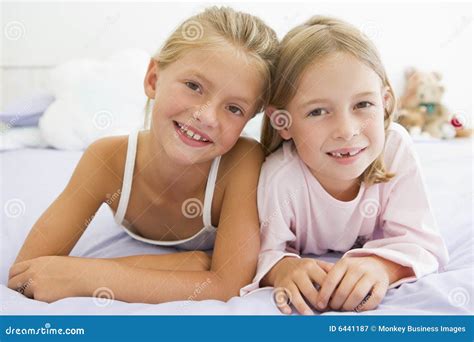 Two Young Girls In Their Pajamas Lying On A Bed Royalty Free Stock Photography - Image: 6441187