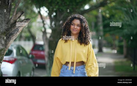 One happy Brazilian young woman walking in city street smiling. A ...