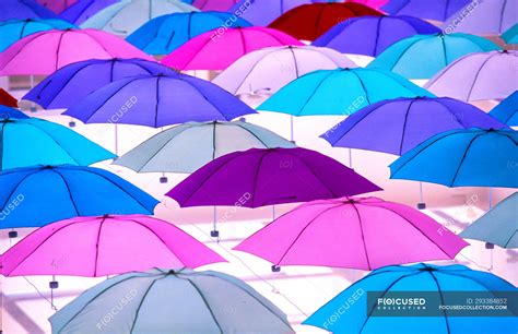 Bright colorful umbrellas hanging on light background, full frame view ...