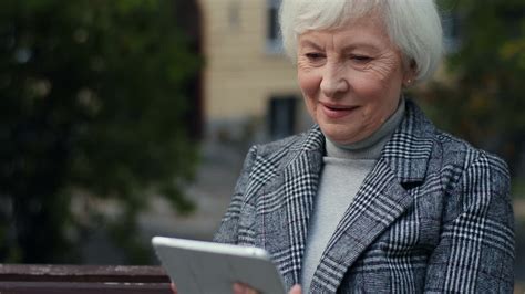 Free stock video - Close up view of ederly woman in the coat sitting on the bench in the park ...