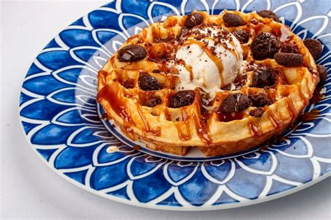 Premium Photo | Round belgian waffle with ice cream and cocoa balls on a decorative plate isolated