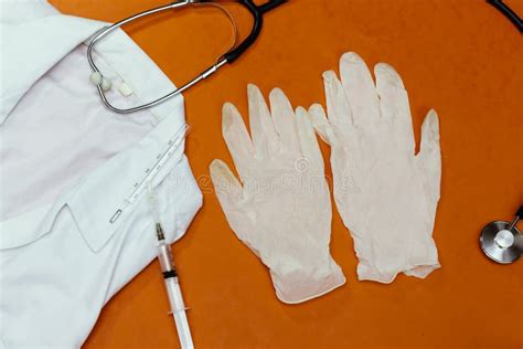 Medical Doctor Apron, Mercury Thermometer and Stethoscope and Medical Gloves Isolated on Orange ...