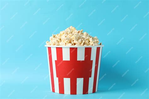 Premium Photo | Striped bucket with popcorn on blue background