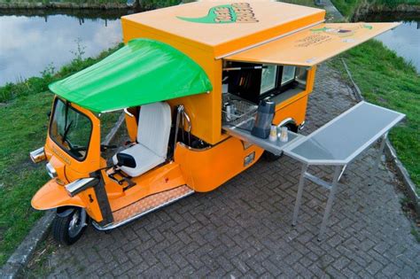 an orange scooter with a green canopy parked next to a small table and ...