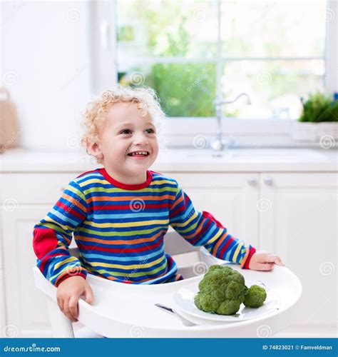 Little Boy Eating Broccoli in White Kitchen Stock Image - Image of eating, bite: 74823021