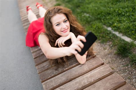 Beautiful Lady In Red Laying Down And Taking A Selfie Stock Photo - Download Image Now - iStock