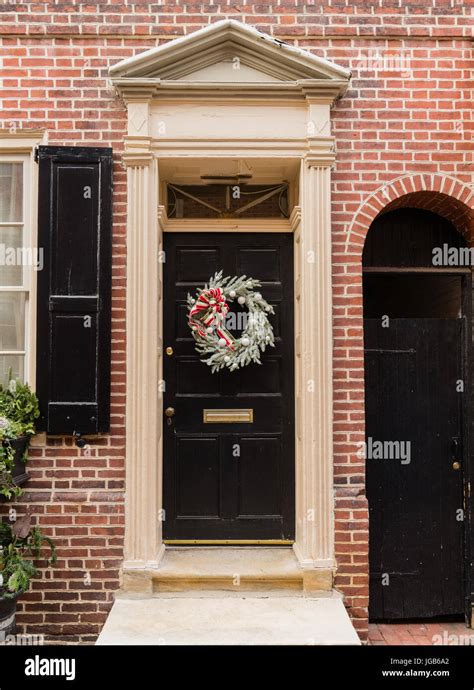 Colonial red doorway in historic Elfreth's Alley in Philadelphia with pediment and christmas ...