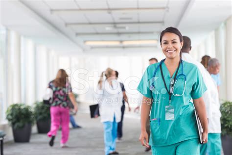 Confident Young Nurse Walking Through Busy Hospital Stock Photo ...