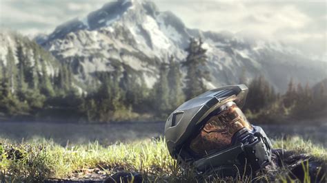 a helmet sitting in the grass with mountains in the background