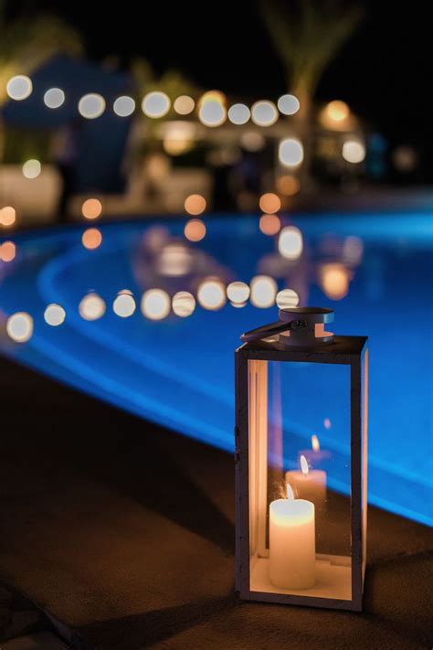 a lit candle sitting next to a pool at night
