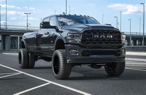 a black ram truck is parked in a parking lot next to an over pass bridge