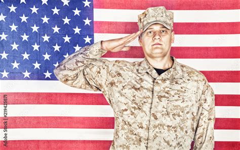 Portrait of U.S. army soldier in camouflage uniform and cap saluting on ...