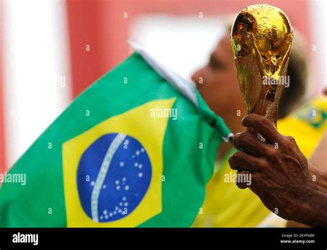 Fifa World Cup trophy replica close up detail and brazilian flag. Soccer fan hand holding award ...