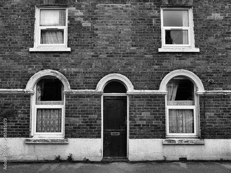 front view of a typical old brick british terraced house with white ...
