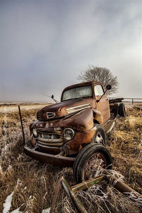 an old rusted truck sitting in a field