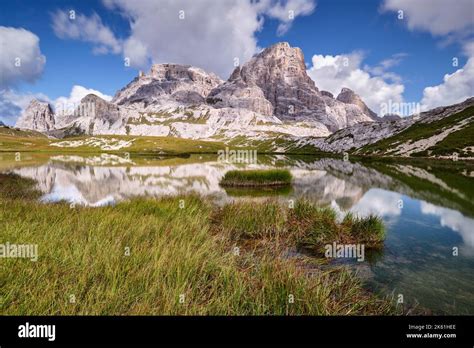 Mount Croda Fiscalina is reflected in the placid waters of the Piani lakes with grass near the ...