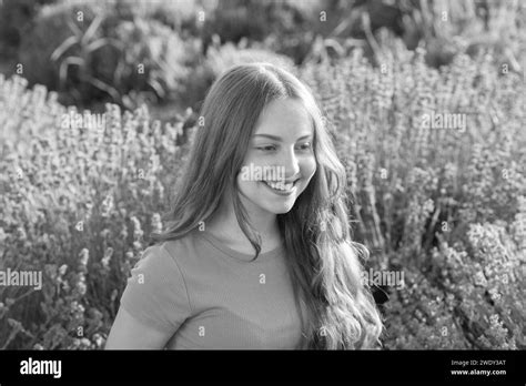 Portrait of a happy young girl with long hair in a lavender field. Girl enjoying blooming ...