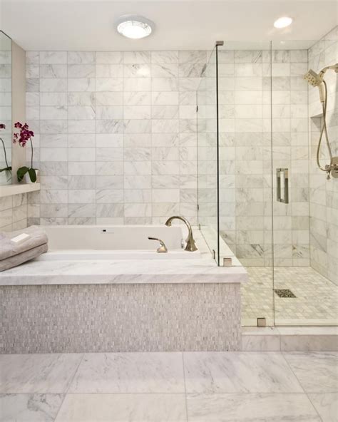 A spa tub sits next to a free standing shower in this contemporary bathroom. The marble tile ...