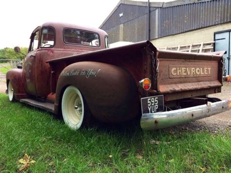 an old truck is parked in the grass near a building with a sign on it