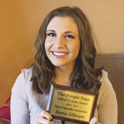 a woman holding up an award plaque in front of her face and smiling at ...