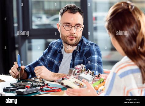 Woman holding circuit board while engineer soldering computer parts Stock Photo - Alamy