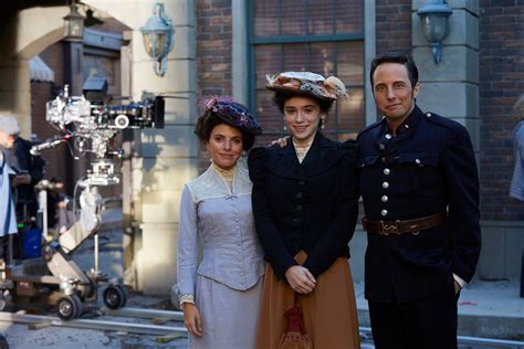 three people standing next to each other in front of an old building with cameras on the street