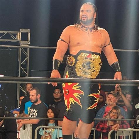 a man standing on top of a wrestling ring in front of a group of people