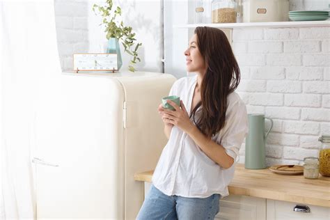 Young happy woman drinking coffee on the kitchen in the morning ...