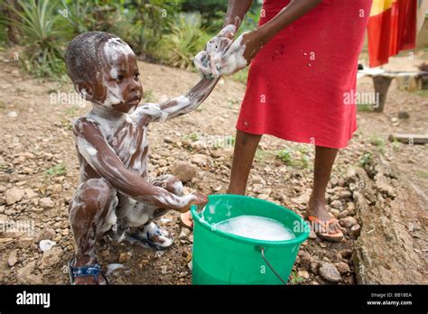 Mother bathing young child out of a bucket, Dakoto Junction, Ghana ...