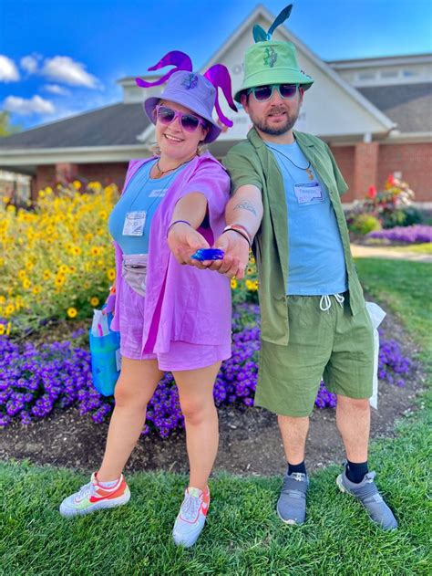 a man and woman dressed up in costume posing for a photo on the grass with flowers behind them