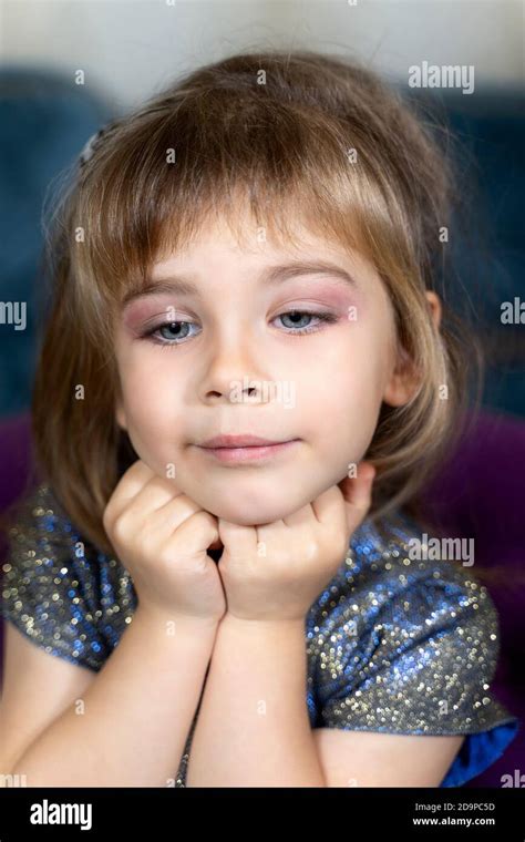 portrait of a beautiful little girl in a blue dress with makeup ...