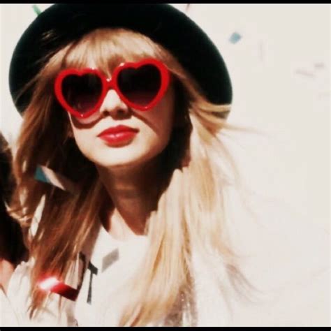 a woman wearing red heart shaped sunglasses and a black hat is standing in front of confetti