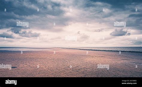 Cuxhaven beach on the German North Sea coast. Sandy beach with Kugelbake, a wooden beacon ...