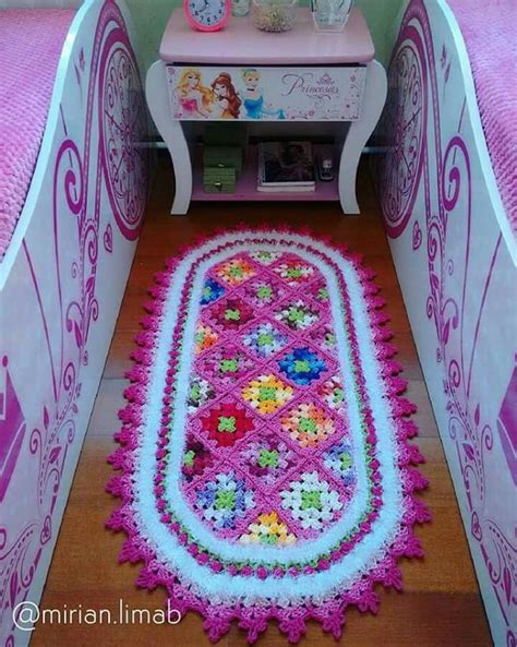 there is a crocheted rug on the floor next to a small table and bed