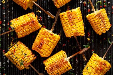 Grilled corn on the cob with butter, herbs, salt and aromatic spices on the grill plate, close ...