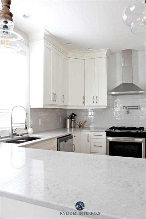 Low contrast white kitchen with Bianco Drift quartz countertops and gray subway tile backsplash ...