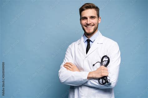 Portrait of confident young medical doctor on blue background. foto de ...