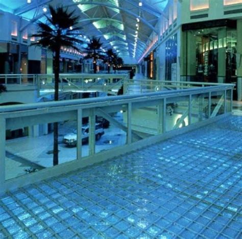 an indoor shopping mall with blue tiles on the floor and palm trees in the background