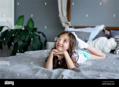 Beautiful little girl lying on bed at house. Portrait of a beautiful ...