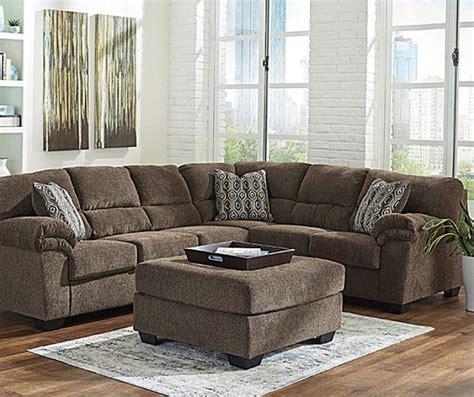 a living room with a sectional couch and ottoman