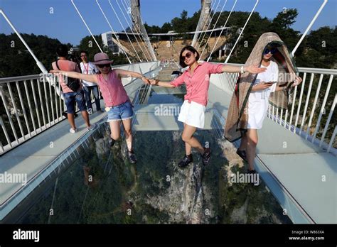 Tourists pose on the world's longest and highest glass-bottomed bridge over the Zhangjiajie ...