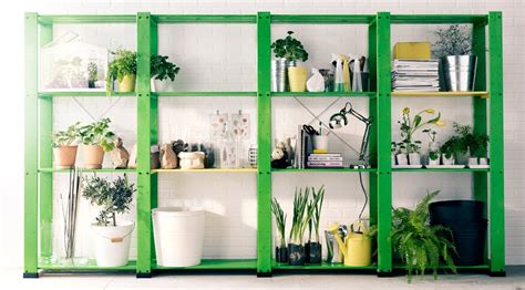 Four wooden shelving units filled with plant pots, plants, flowers, vases and watering cans ...