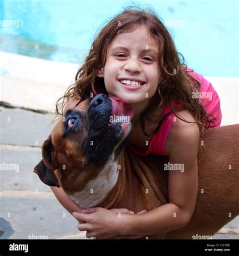 Young girl smiles and hugs dog (boxer) while it licks her in the face Stock Photo - Alamy