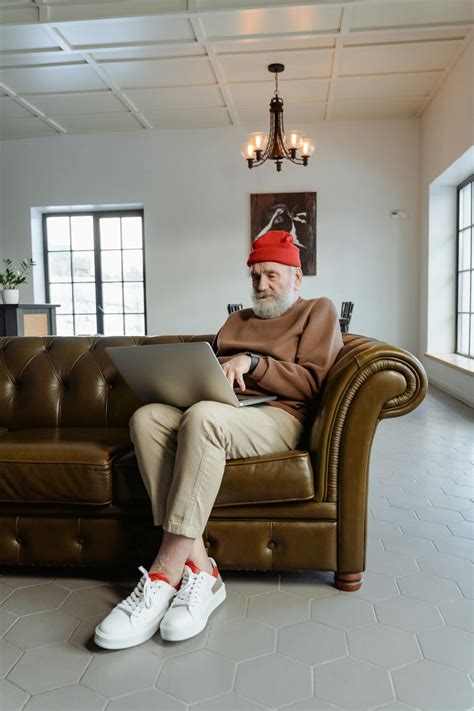 Man in Brown Sweater Sitting on Brown Leather Sofa Chair Using a Laptop · Free Stock Photo