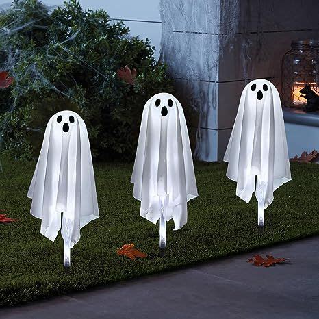 three white ghost decorations in the grass