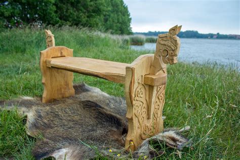a carved wooden bench sitting on top of a grass covered field next to a ...