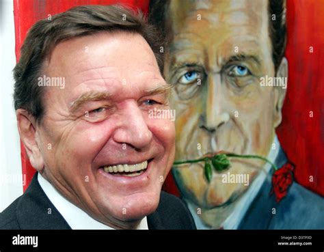 Former chancellor Gerhard Schroeder stands in front of a portrait that shows him with a rose in ...