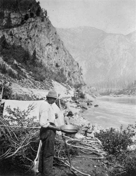 an old black and white photo of a man standing on the side of a mountain