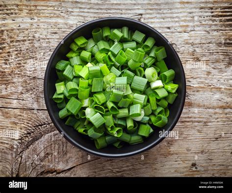 Bowl of chopped spring onions on wooden table, top view Stock Photo - Alamy
