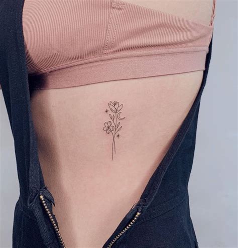 Fine line flower tattoo on rib